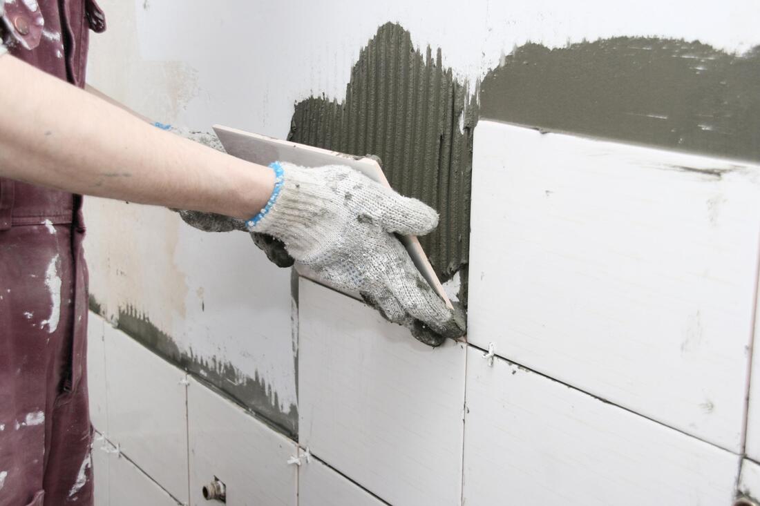 someone's hand installing a wall tile